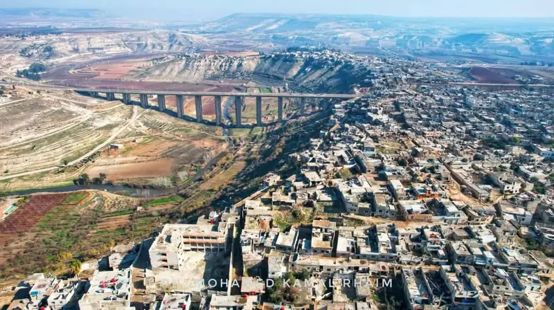 جسر الرستن والمدينة على حافة الوادي — لقطة جوّية