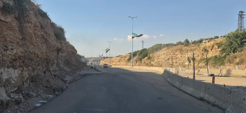 المدخل الصخريّ والأعلام على جانبي الطريق